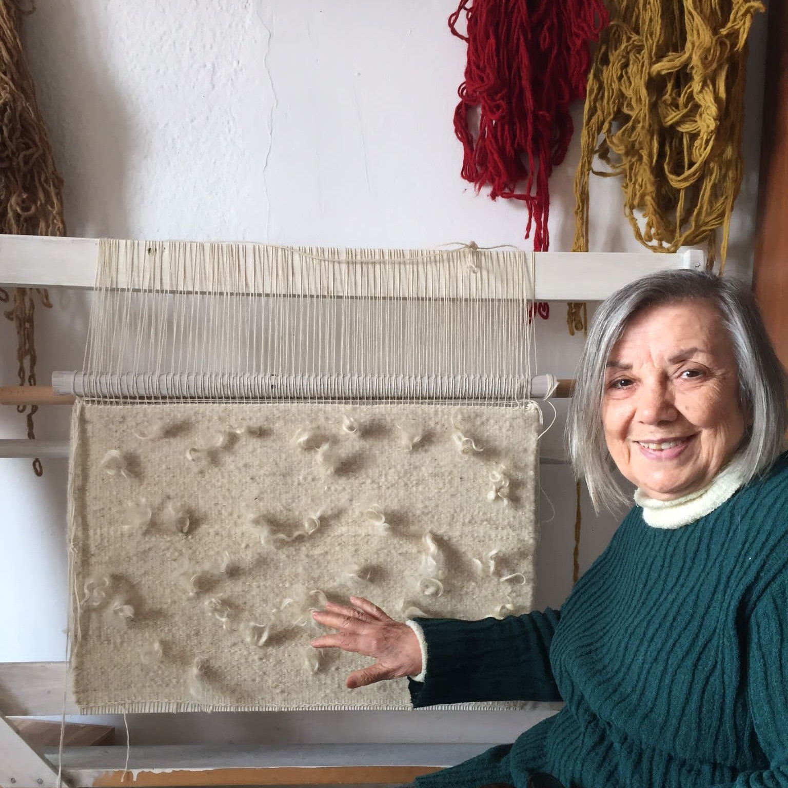 product page bulletin, woman posing while working on traditional rug loom